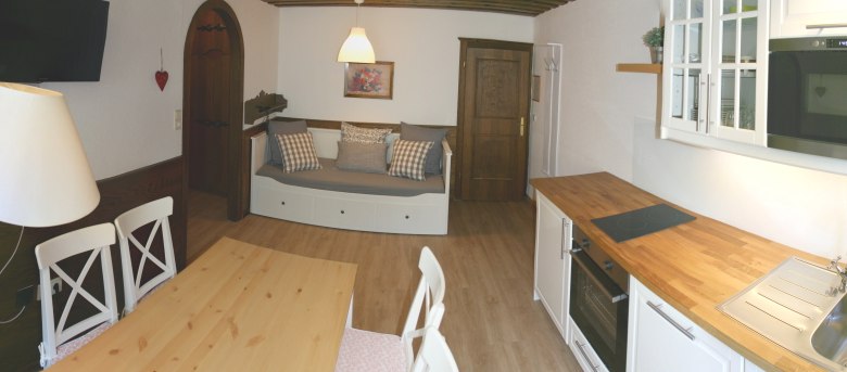 Apartment 4, © Marianne Gschaider Cozy apartment with wooden furniture, dining table, sofa and kitchenette.