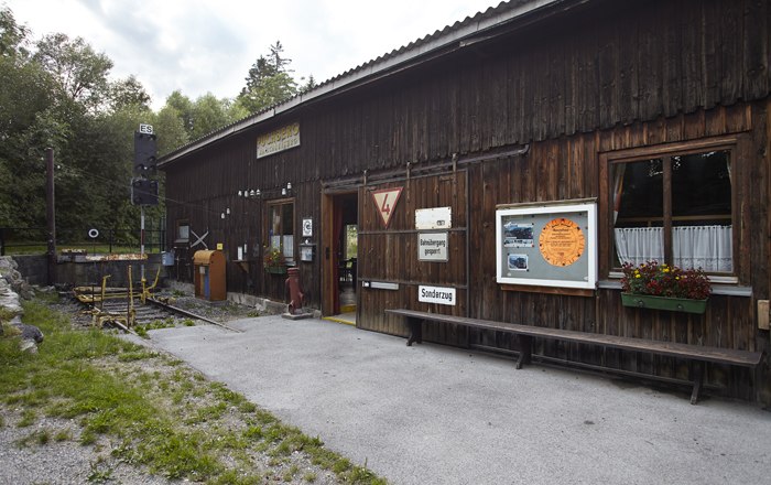 Zahnradbahnausstellung, © Wiener Alpen, Foto: Bene Croy Holzgebäude mit Schildern und Blumen, Teil einer Ausstellung.