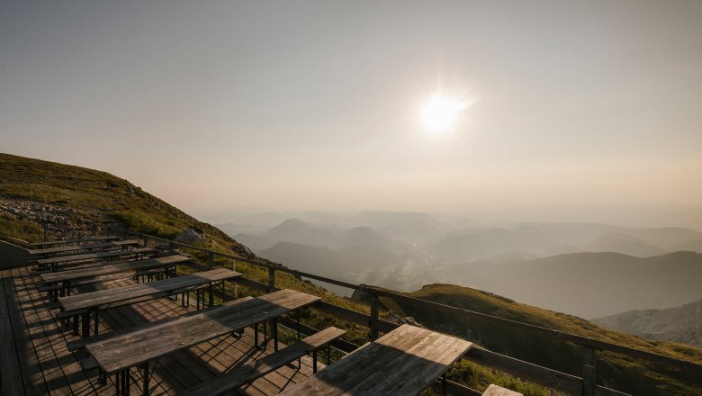 Fischerhütte, Schneeberg, Hütte, Schneebergland, Wiener Alpen in Niederösterreich, © Wiener Alpen/Sophie Menegaldo Sonnenterrasse der Fischerhütte am Schneeberg mit Holztischen und weitem Blick über die Berglandschaft