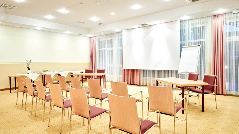 Seminar room Hotel Schneeberghof, © Hotel Schneeberghof A bright seminar room with chairs, tables, a flipchart and a projection screen.