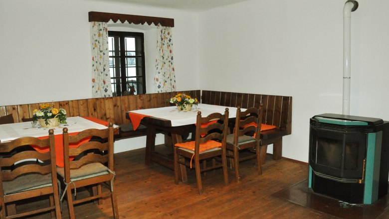 Ferienhaus Haltberghof, © Claudia Alber Gemütlicher Essbereich mit Holztisch, Stühlen, Eckbank und Ofen.