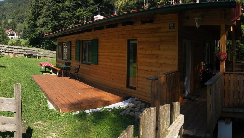 Ferienhaus, © Marianne Gschaider Ein Holzferienhaus mit Terrasse in einer grünen, bewaldeten Umgebung.