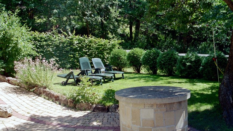 Garten: Liegewiese, © Haus Lenz Garten mit Liegestühlen und Brunnen auf einer Wiese.