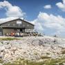 Fischerhütte auf 2049m, © WA/Franz Zwickl Fischerhütte auf dem Schneeberg mit Wanderern und blauem Himmel.