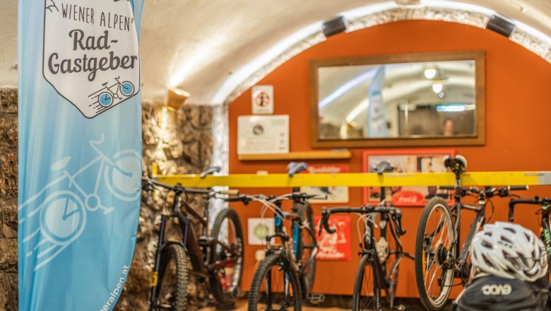Bike garage at the Landgasthof zur Schubertlinde, © Wiener Alpen/Martin Fülöp Bicycle garage with bicycles and a banner of the Vienna Alps bike hosts.