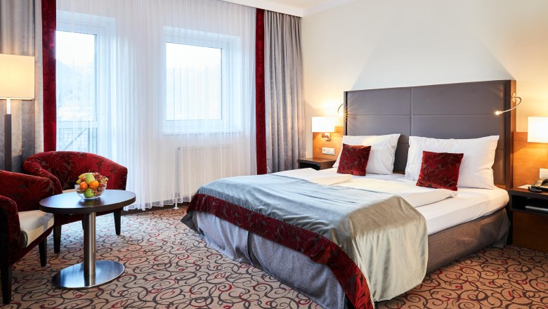 Double room Hotel Schneeberghof, © Hotel Schneeberghof Double room at Hotel Schneeberghof with double bed, red pillows, table with fruit bowl and two armchairs.