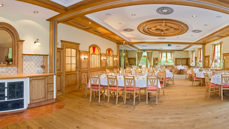 Saal, © Patrick Haberler Eleganter, holzverkleideter Speisesaal mit gedeckten Tischen und großen Fenstern.