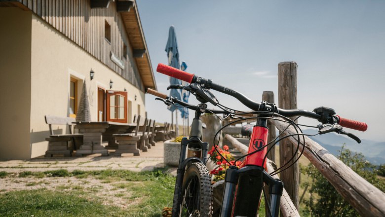 Almreserlhaus, Schneeberg, Hütte, Schneebergland, Wiener Alpen in Niederösterreich, © Wiener Alpen/Sophie Menegaldo Mountainbike vor dem Almreserlhaus am Schneeberg mit Sitzbänken im Hintergrund