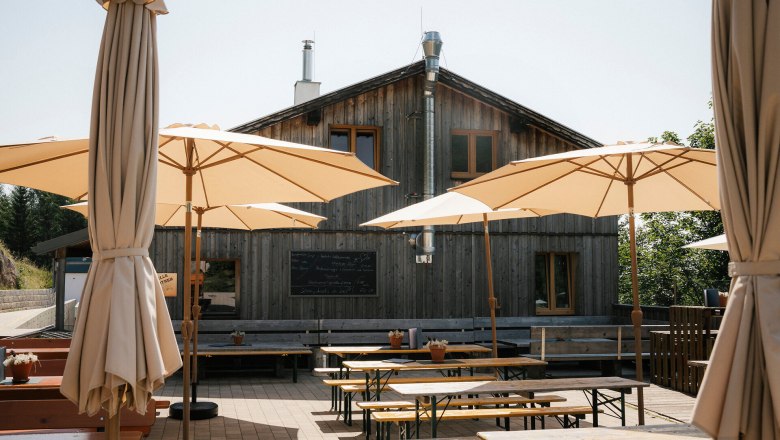 Schutzhütte Haltestelle Baumgartner, Schneeberg, Hütte, Schneebergland, Wiener Alpen in Niederösterreich, © Wiener Alpen/Sophie Menegaldo Terrasse der Schutzhütte Haltestelle Baumgartner mit Sitzbänken und großen Sonnenschirmen