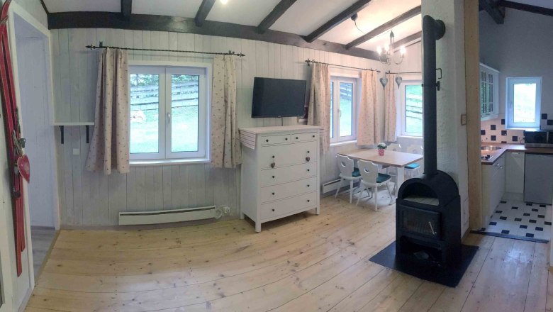 Vacation home, © Marianne Gschaider Interior view of a cozy vacation home with wood-burning stove, dining table, chest of drawers and kitchen.