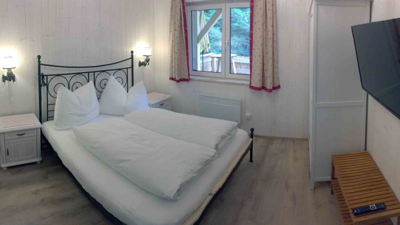 Vacation home, © Marianne Gschaider Bedroom with double bed, TV and window with curtains.