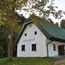 Wei&szlig;es Ferienhaus mit gr&uuml;nem Dach im Wald, beschriftet mit 'Haltberghof'.