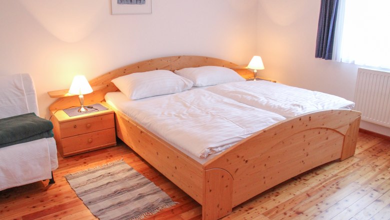 Cozy bedroom with double bed, wooden floor and bedside tables with lamps.
