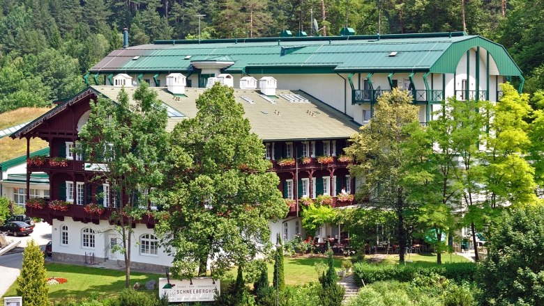 A large hotel building with green roofs and balconies, surrounded by trees and nature.