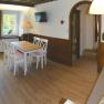 Gem&uuml;tliches Wohnzimmer mit Holzboden, Esstisch, Sofa und K&uuml;chenzeile.