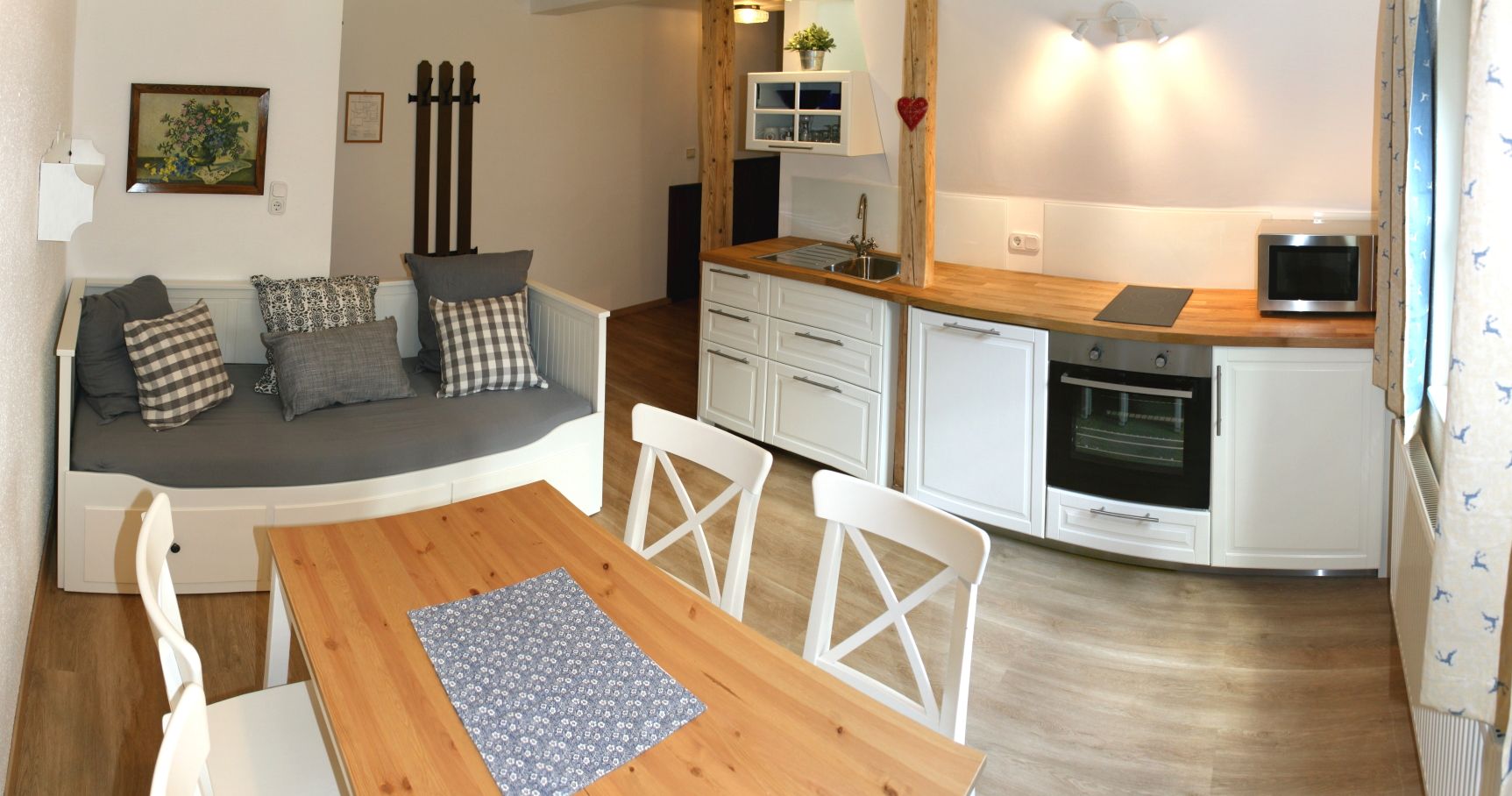 Gemütliche Küche mit Holztisch, weißen Stühlen, Sofa und moderner Küchenzeile.