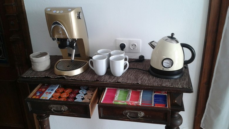 Coffee machine and kettle on a table with cups and tea bags.