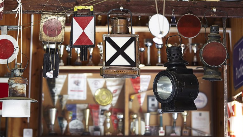 Verschiedene alte Eisenbahnlampen und Signale hängen in einer Ausstellung.