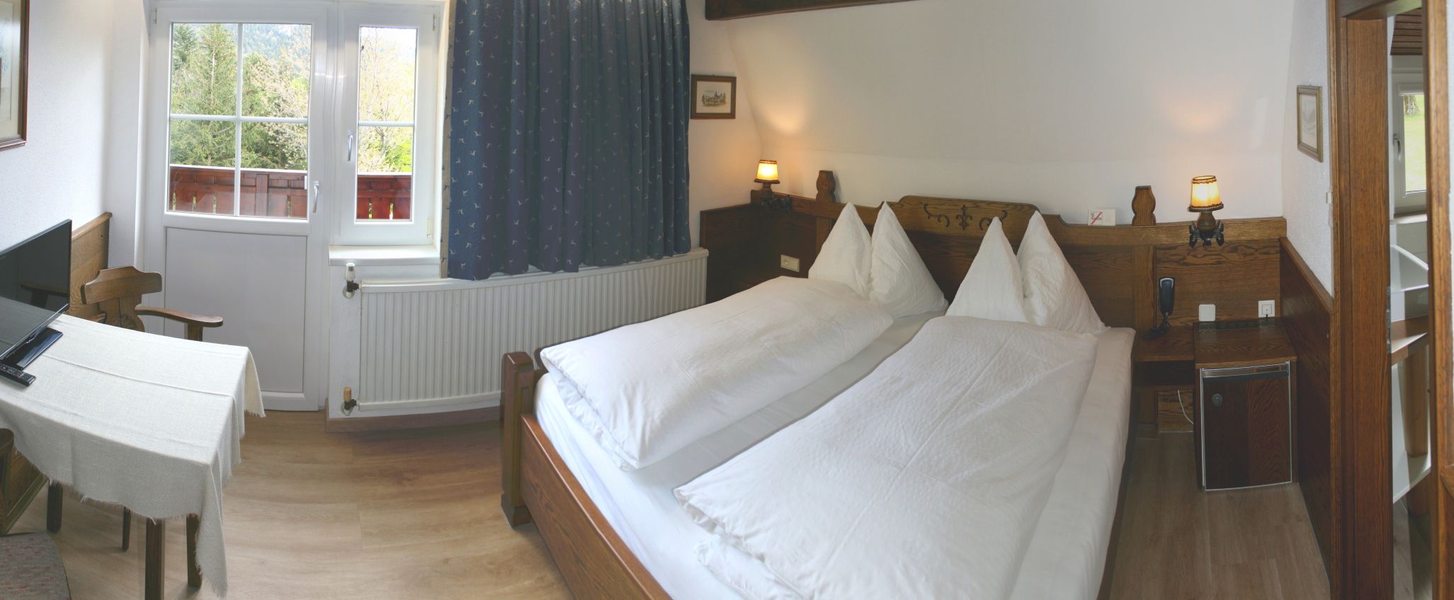 Gemütliches Schlafzimmer mit Doppelbett, Holzmöbeln und Fenster mit Blick ins Grüne.