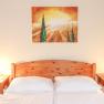Schlafzimmer mit Holzbett, zwei Nachttischen und einem Landschaftsbild an der Wand.