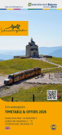 Snow Mountain Railway train on mountain route in front of mountain station with building, blue sky in the background.