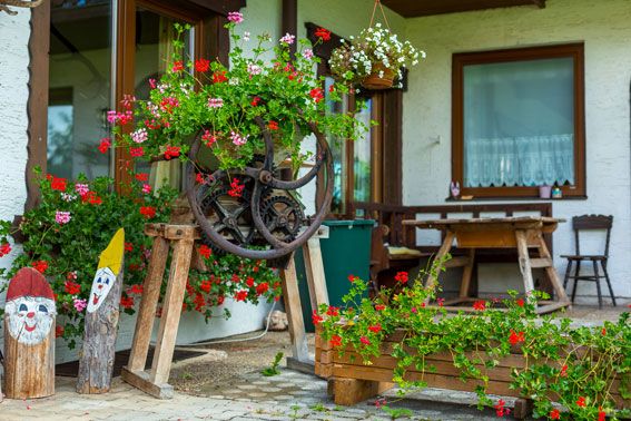 Ein rustikaler Garten mit Blumen und Holzdekorationen vor einem Gebäude.