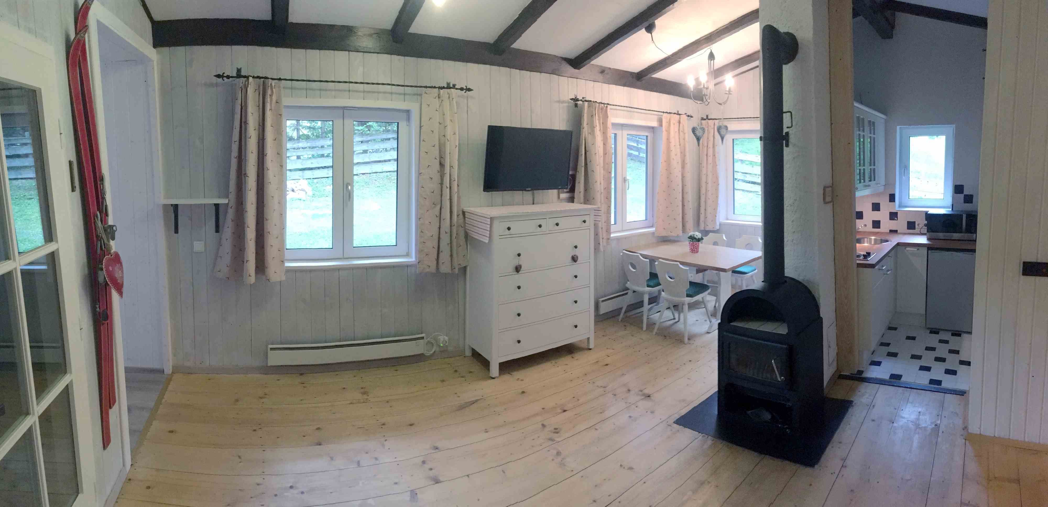 Innenansicht eines gemütlichen Ferienhauses mit Holzofen, Esstisch und Küche.