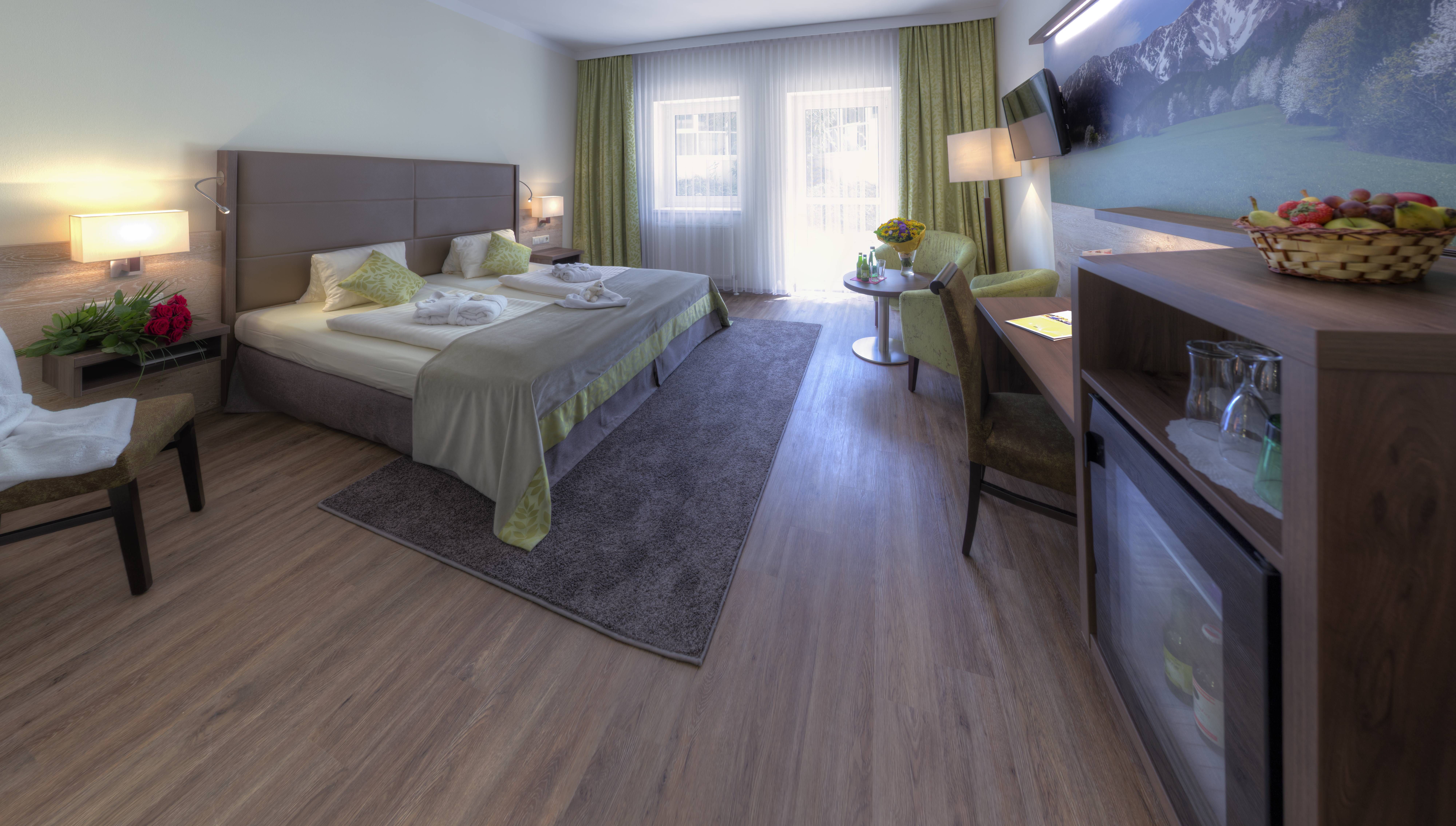 Elegantes Hotelzimmer mit Doppelbett, Sitzbereich und großem Fenster.