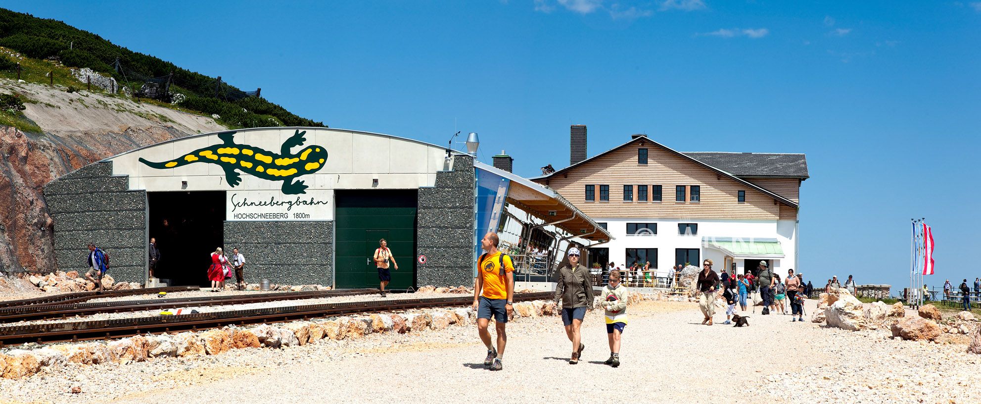 Eingang der Schneebergbahn am Hochschneeberg mit Menschen und Berghaus im Hintergrund.