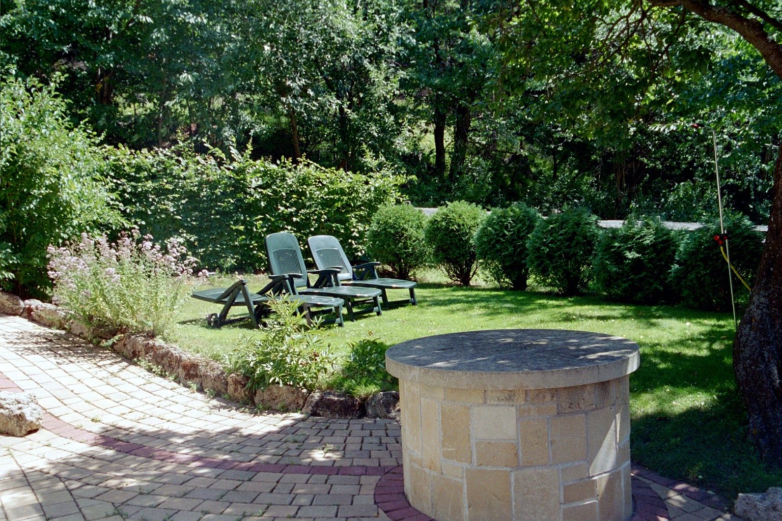 Garten mit Liegestühlen und Brunnen auf einer Wiese.