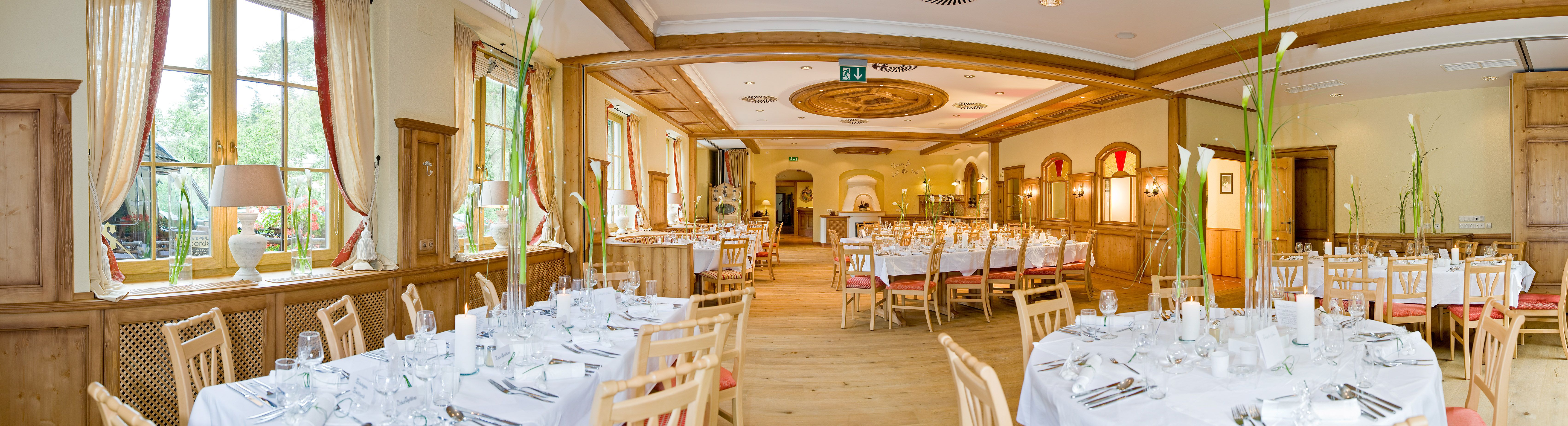 Eleganter Speisesaal mit gedeckten Tischen und Holzverkleidung.
