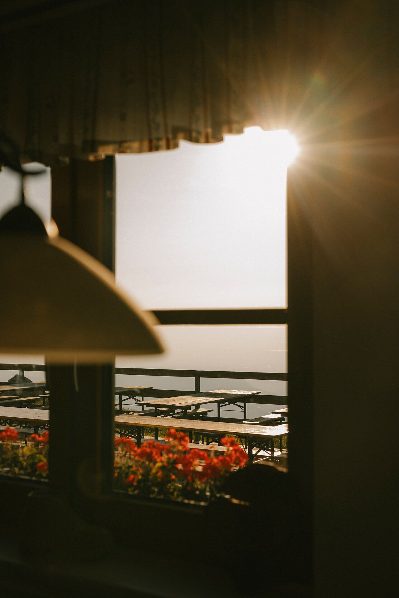 Sonnenlicht fällt durch das Fenster der Fischerhütte am Schneeberg auf die Terrasse mit Sitzbänken
