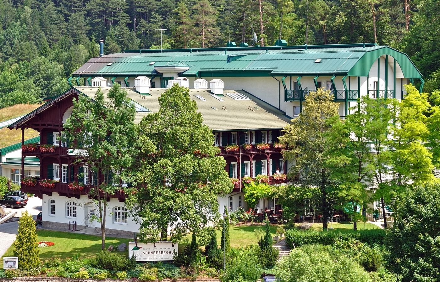 Ein großes Hotelgebäude mit grünen Dächern und Balkonen, umgeben von Bäumen und Natur.