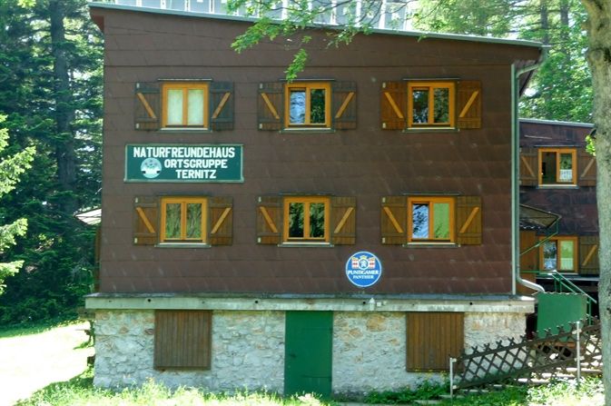 Ein dreistöckiges Gebäude mit Holzfensterläden und Schildern der Naturfreunde Ternitz.