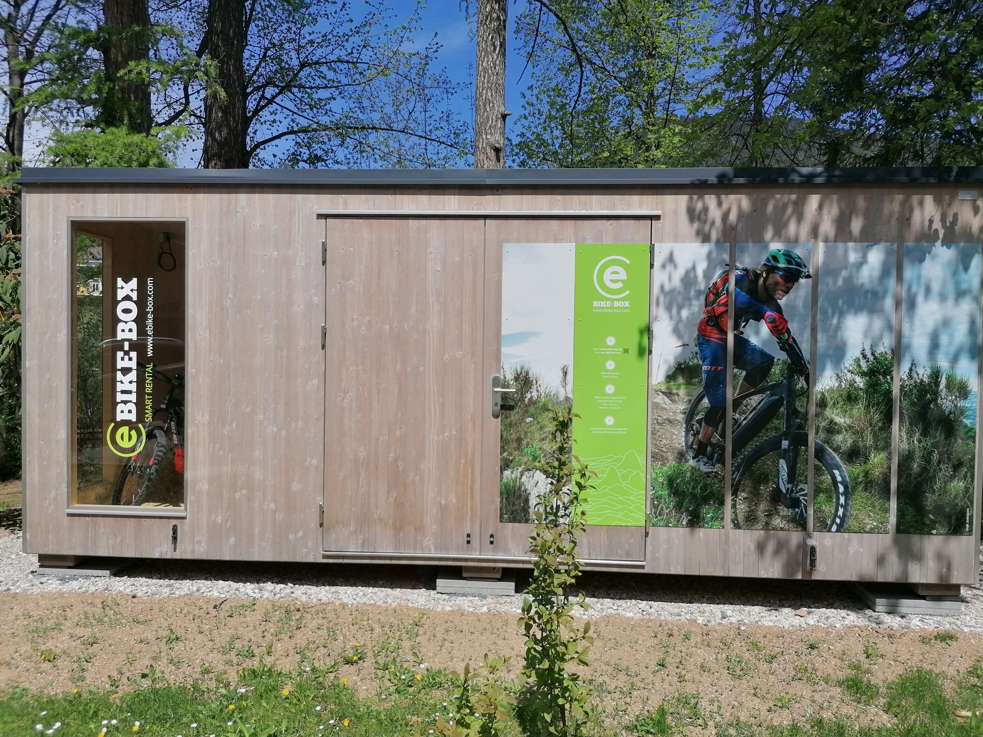 Holzhütte mit E-Bike-Werbung und Bild eines Radfahrers.