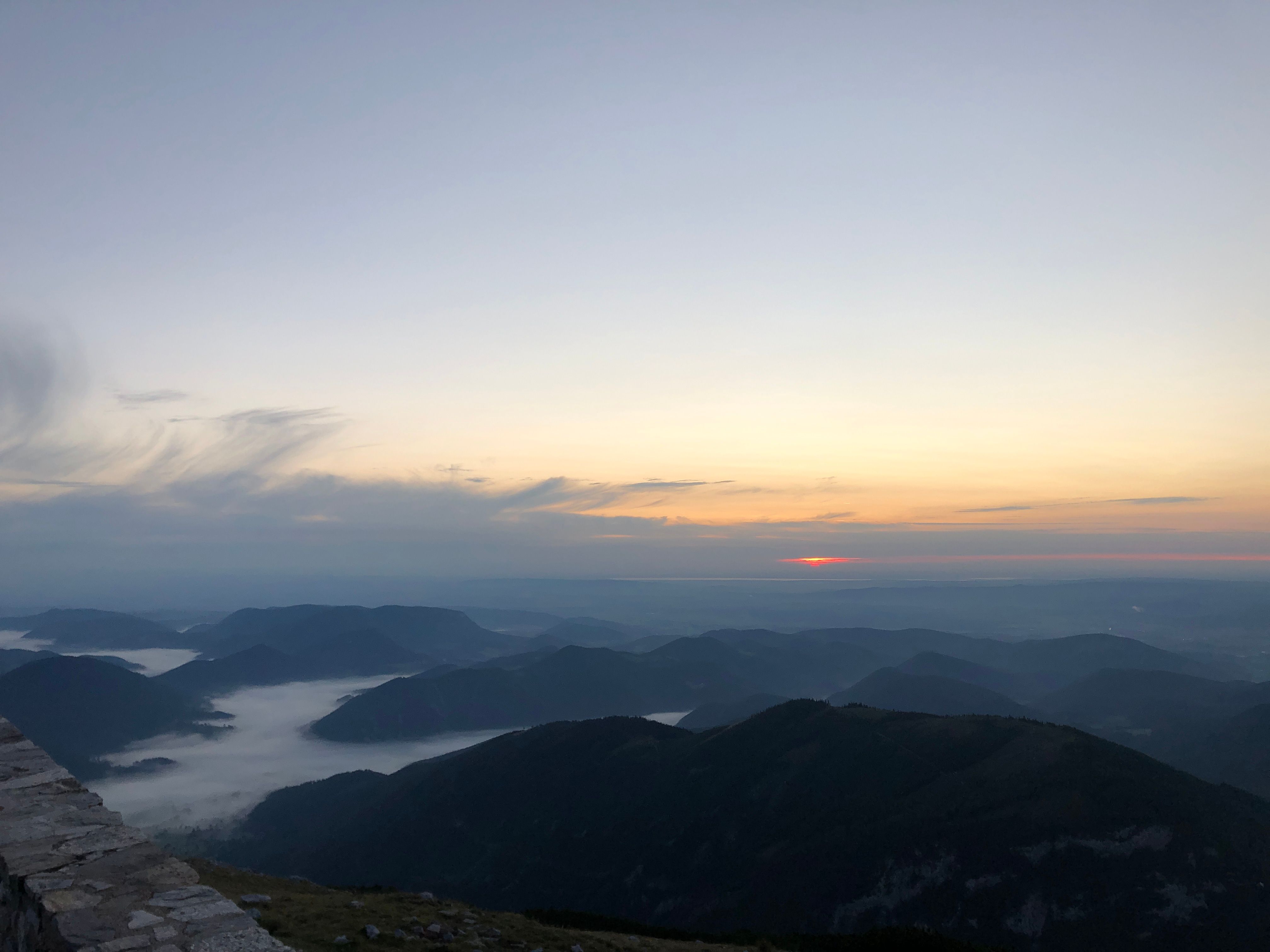 Berglandschaft mit Nebel in den Tälern und Sonnenaufgang am Horizont
