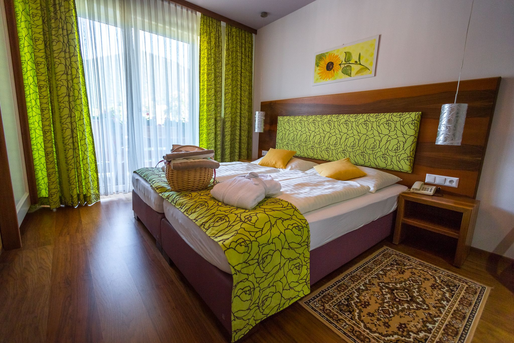 Zimmer mit Doppelbett, Holzboden und grünen Vorhängen