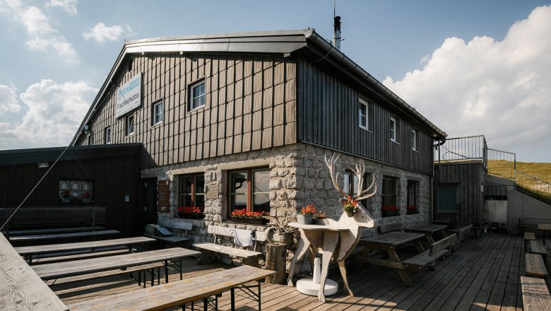 Fischerhütte, Schneeberg, Hütte, Schneebergland, Wiener Alpen in Niederösterreich, © Wiener Alpen/Sophie Menegaldo Fischerhütte am Schneeberg mit Terrasse, Sitzbänken und dekorativer Steinbockfigur vor dem Gebäude