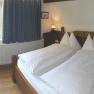 Gem&uuml;tliches Schlafzimmer mit Doppelbett, Holzm&ouml;beln und Fenster mit Blick ins Gr&uuml;ne.