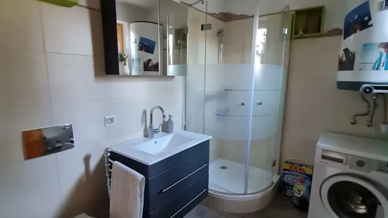 Modern bathroom with shower, washbasin, toilet and washing machine.