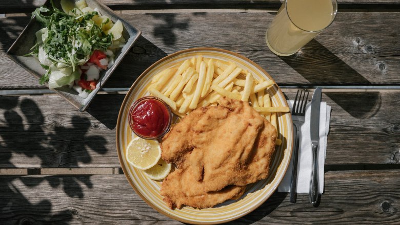 Schnitzel mit Pommes frites, Salat und Getr&auml;nk auf einem Holztisch beim Damb&ouml;ckhaus am Schneeberg