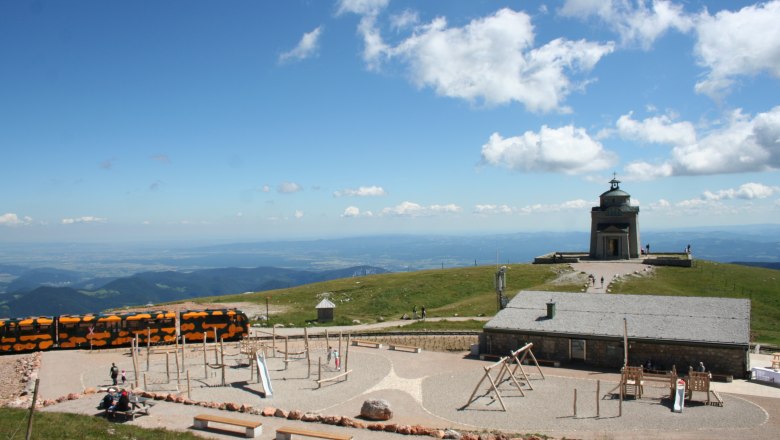 Alter Bergbahnhof mit Spielplatz im Vordergrund. Der Salamander-Zug steht davor.