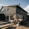 Fischerh&uuml;tte am Schneeberg mit Terrasse, Sitzb&auml;nken und dekorativer Steinbockfigur vor dem Geb&auml;ude