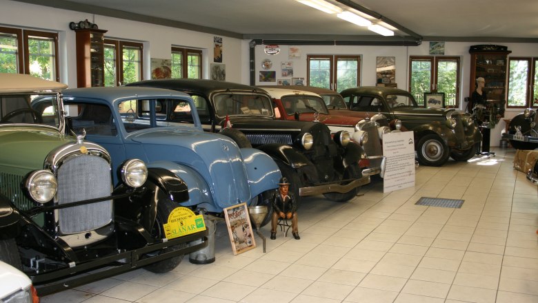 Interior view of a classic car museum with several classic cars in a row.