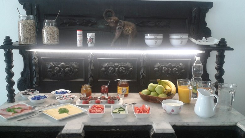 Fr&uuml;hst&uuml;cksbuffet mit Obst, Aufschnitt, K&auml;se, Marmelade und Getr&auml;nken auf einem dekorativen Tisch.