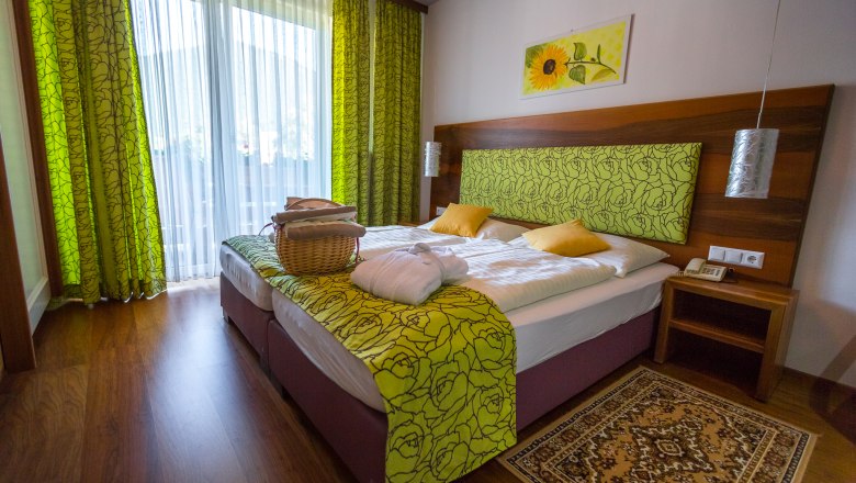 Room with double bed, wooden floor and green curtains