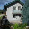 Ein graues Haus mit gr&uuml;nem Dach und kleinem Garten im Vordergrund.