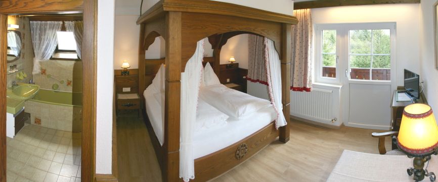 Gemütliches Schlafzimmer mit Himmelbett, angrenzendem Badezimmer und Balkonzugang.