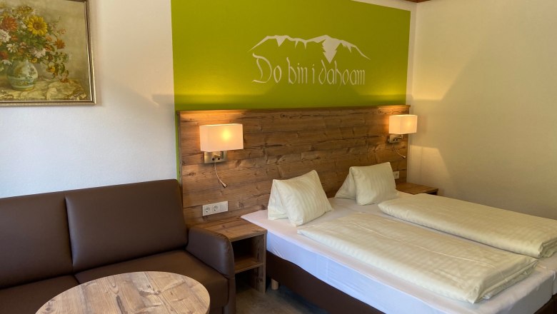 Cozy double room with wooden furniture, sofa, table and wall decoration.