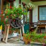 A rustic garden with flowers and wooden decorations in front of a building.